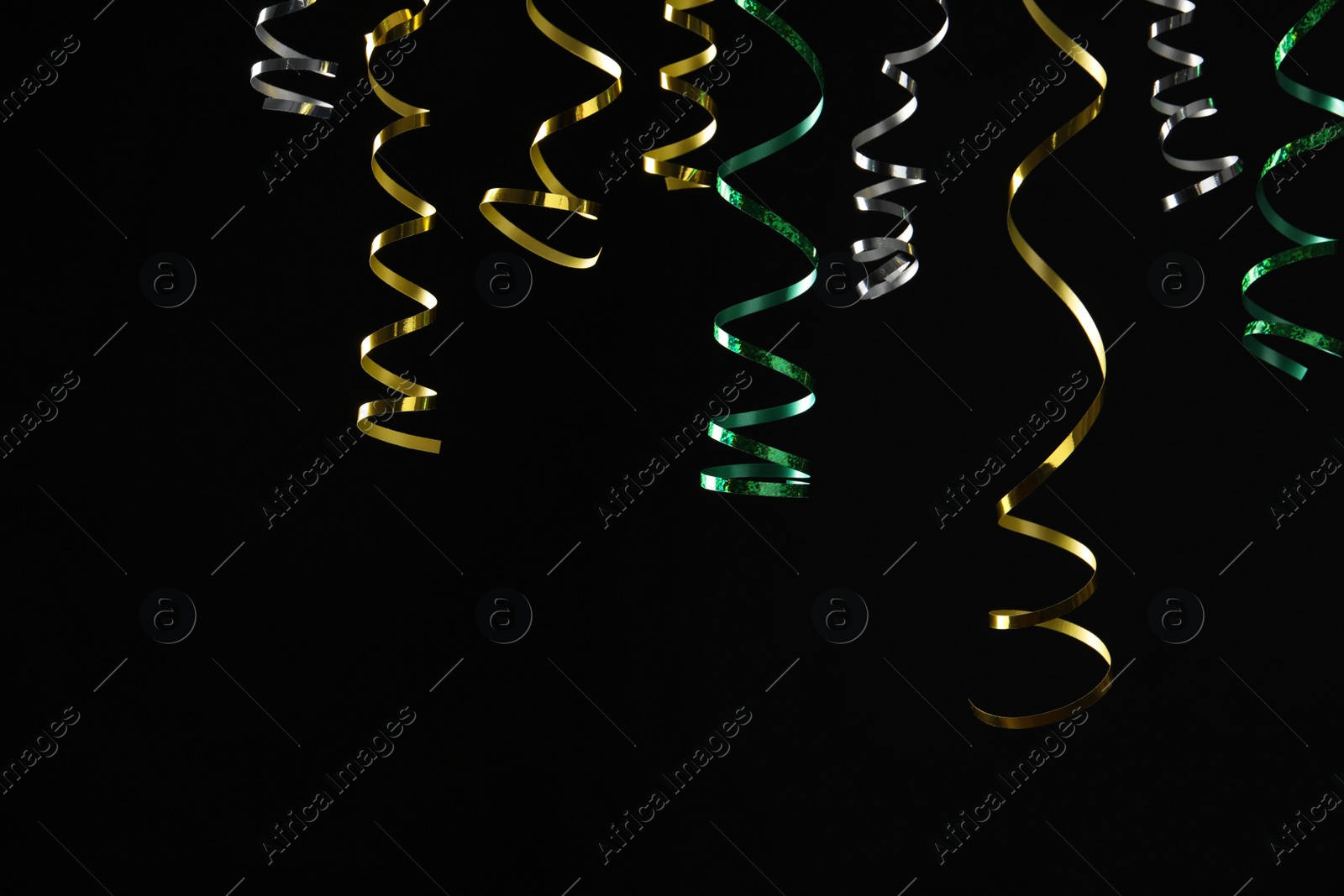 Photo of Many colorful serpentine streamers on black background