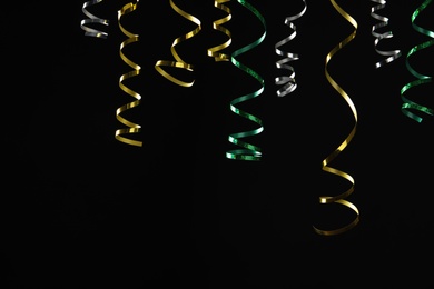 Photo of Many colorful serpentine streamers on black background