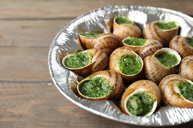 Photo of Delicious cooked snails on wooden table, closeup