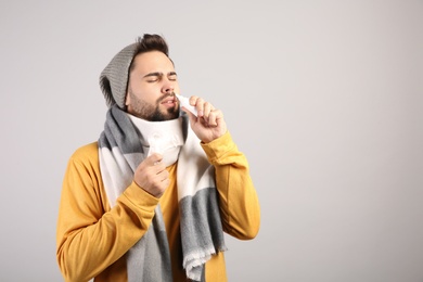 Photo of Man using nasal spray on light grey background, space for text