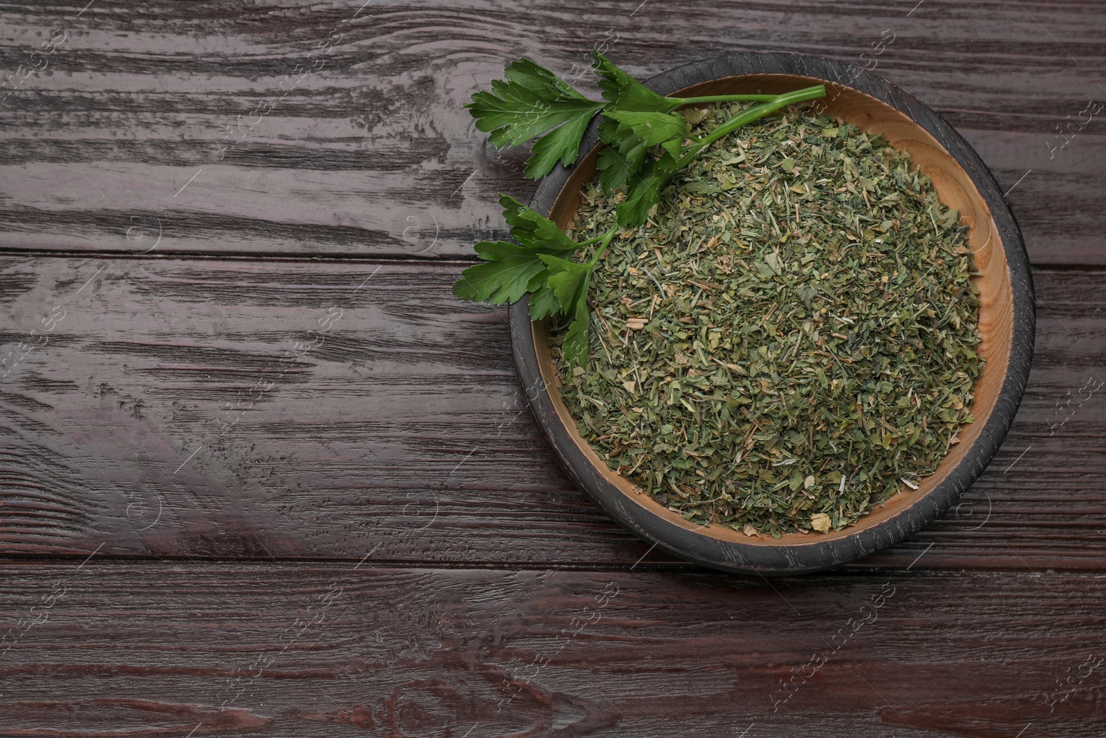 Dried aromatic parsley and fresh leaves in plate on wooden table, top view. Space for text Photo of Dried aromatic parsley and fresh leaves in plate on wooden table, top view. Space for text