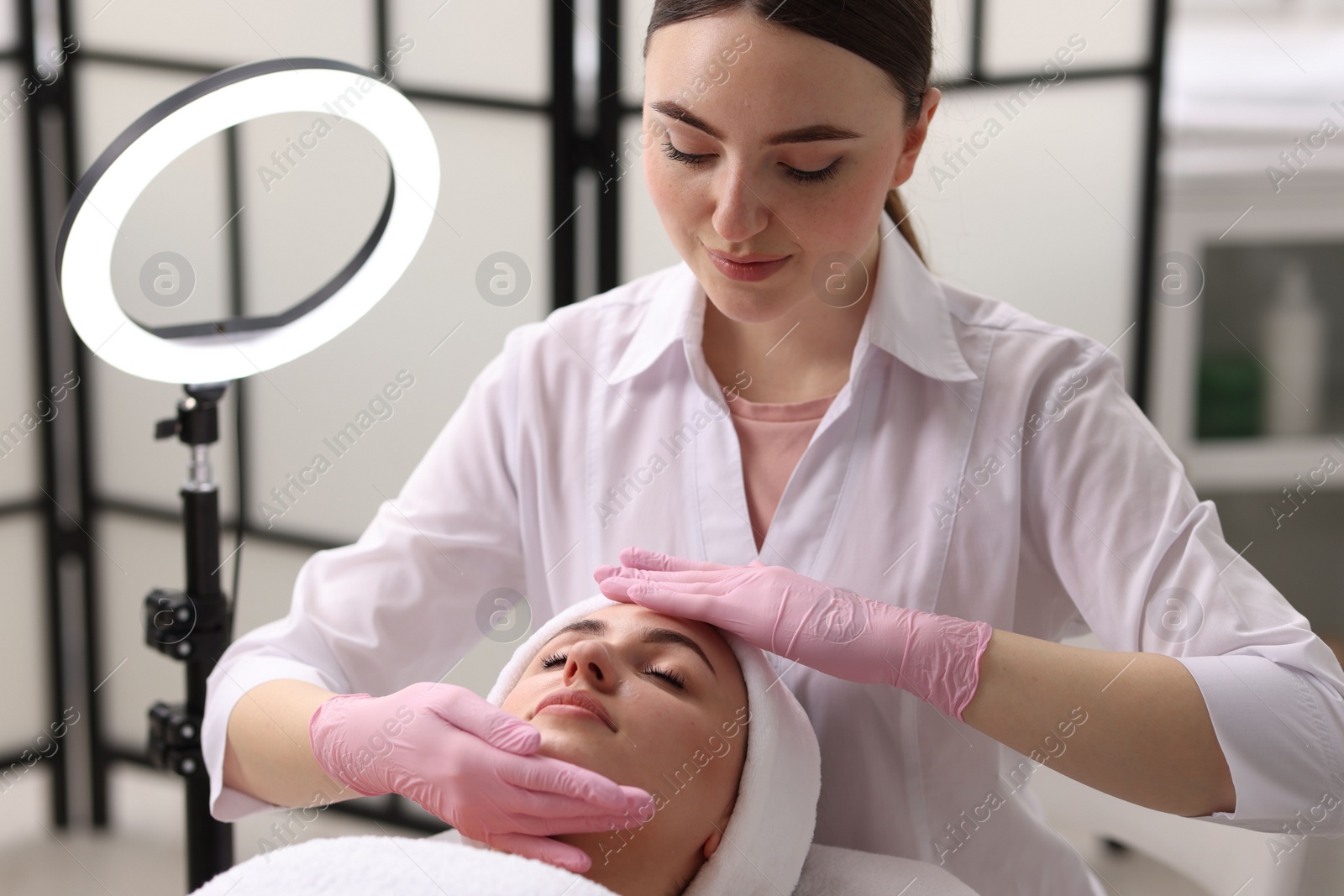 Photo of Cosmetologist making face massage to client in clinic