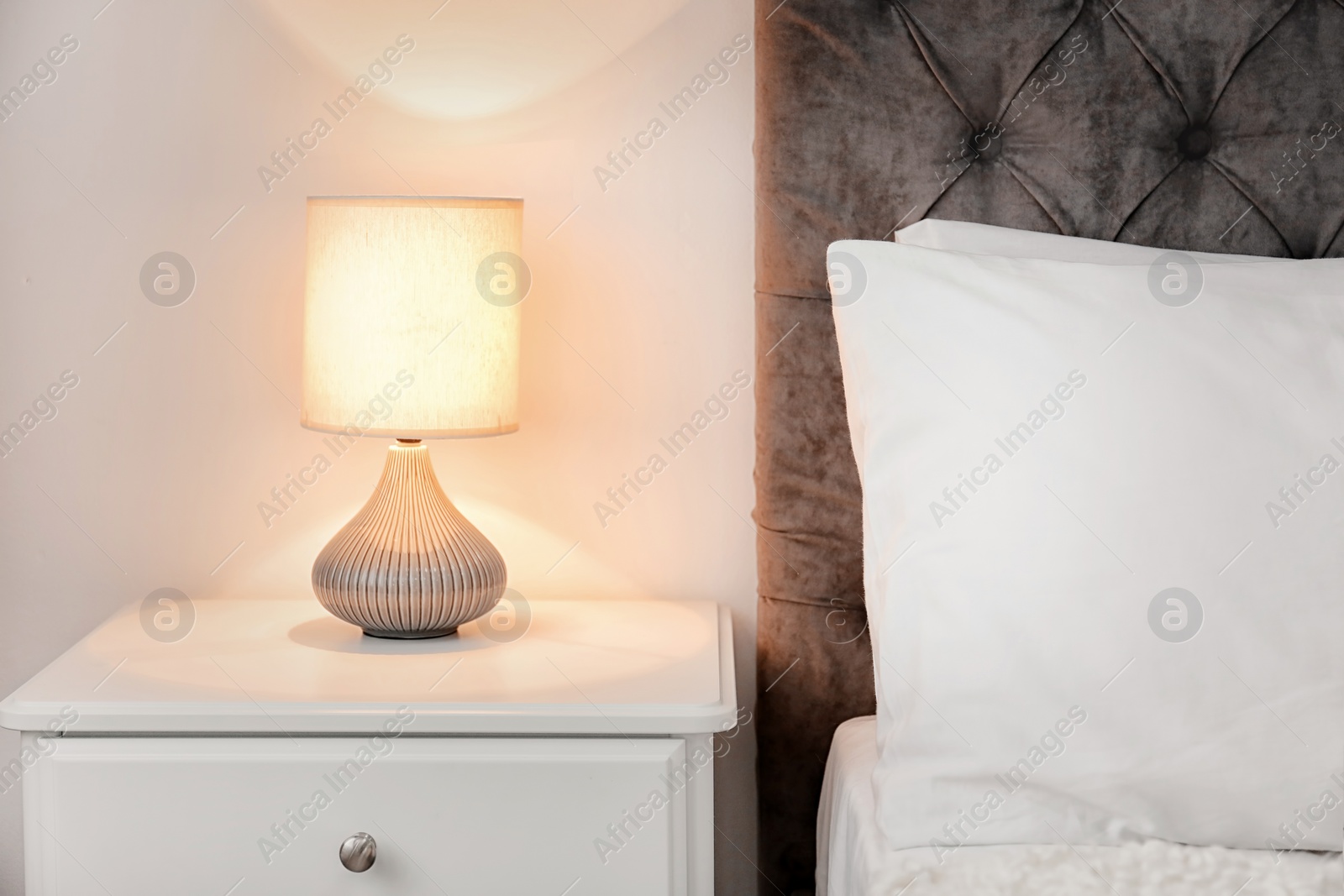 Photo of Lamp on bedside table in modern hotel room