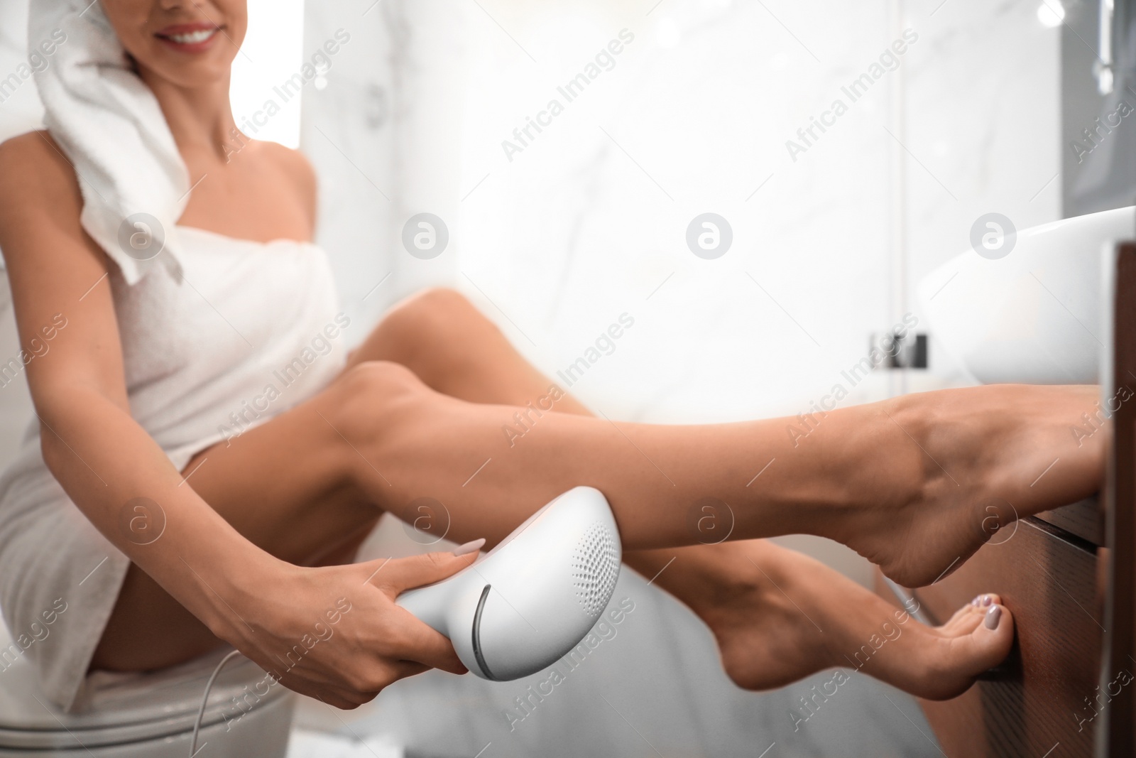 Photo of Young woman epilating her legs in bathroom, closeup