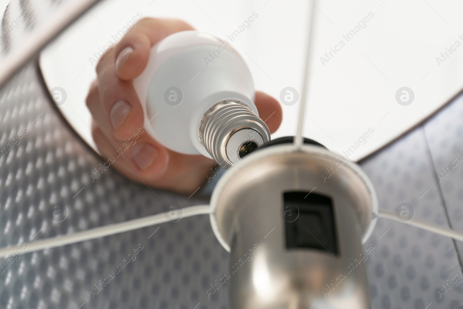 Photo of Man changing light bulb in lamp, closeup. Low angle view