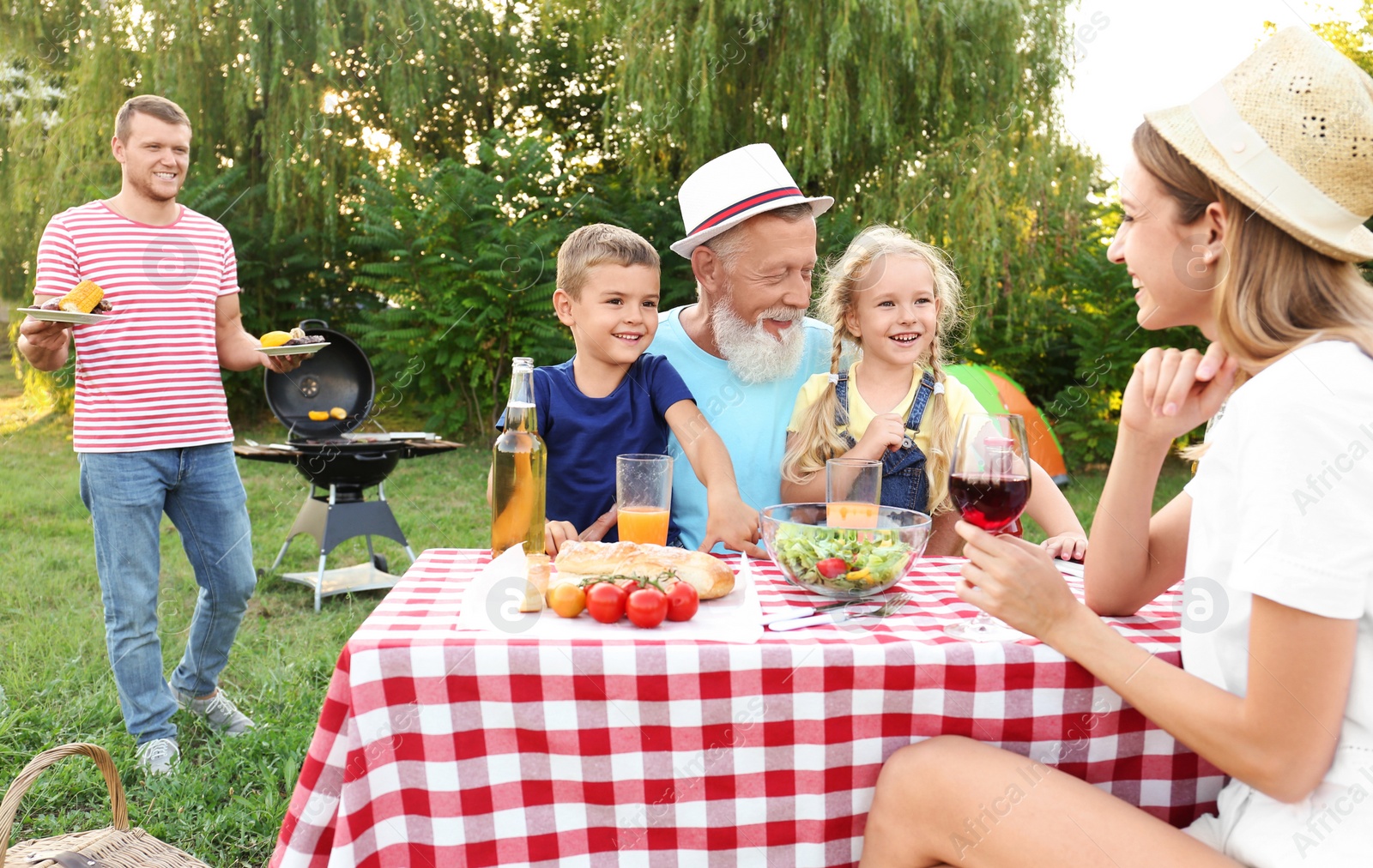 Photo of Happy family having barbecue in park on sunny day