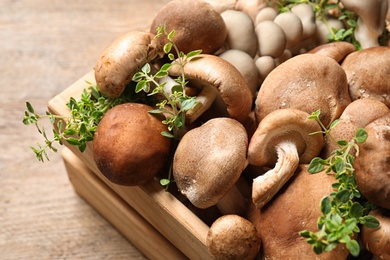 Photo of Different wild mushrooms in crate on wooden table, closeup