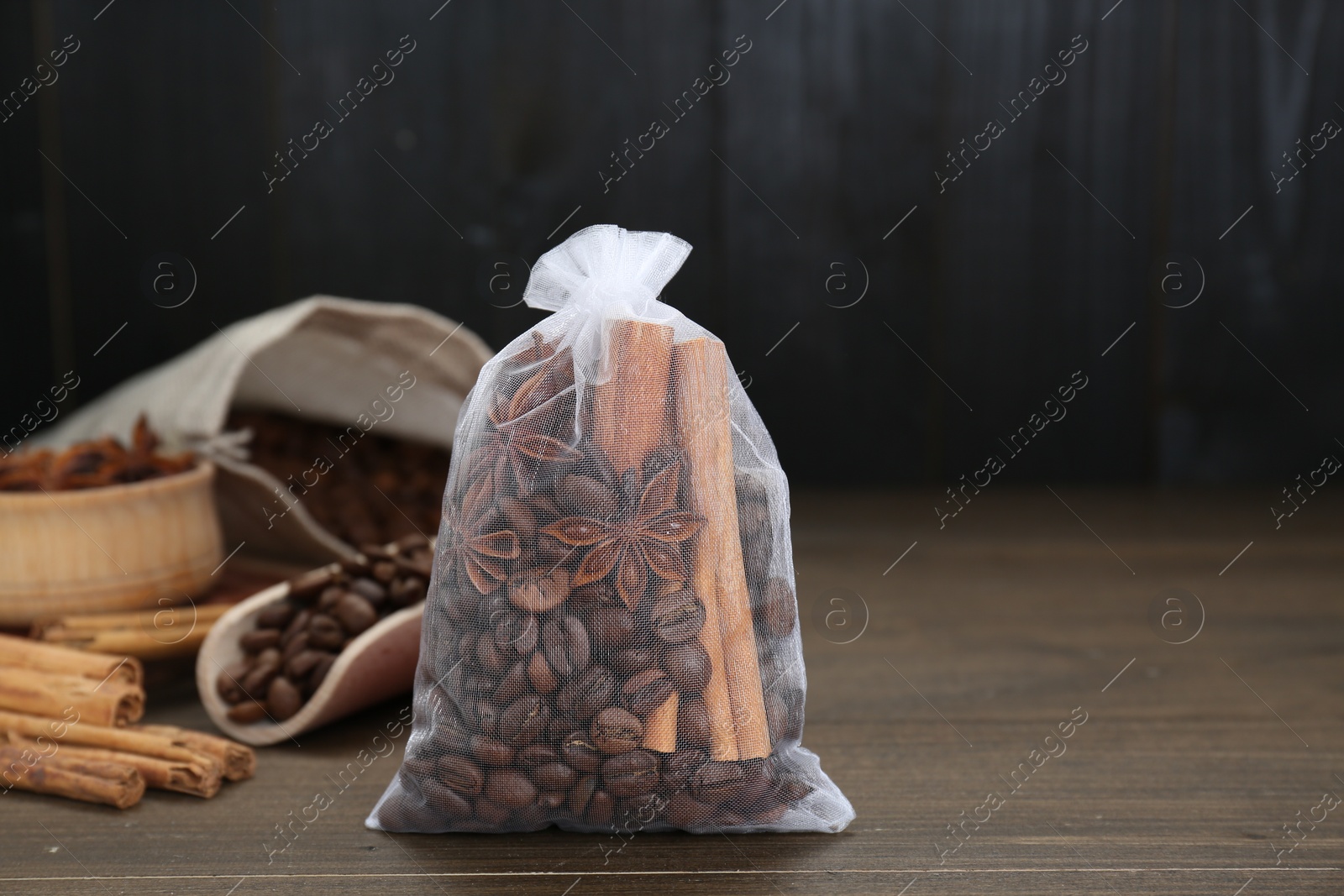 Photo of Scented sachet with coffee beans, anise and cinnamon on wooden table, closeup