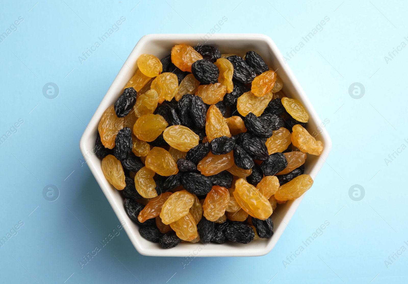 Photo of Bowl with raisins on color background, top view. Dried fruit as healthy snack