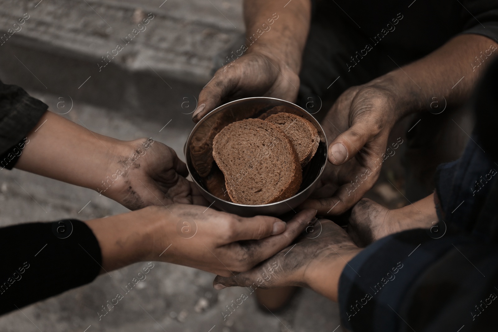 Photo of Poor homeless people with pieces of bread outdoors, closeup