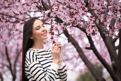 Photo of Pretty young woman near blooming tree in park. Spring look