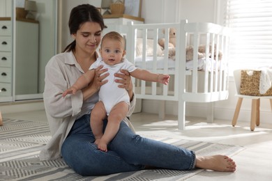 Photo of Happy young mother with her baby in nursery. Space for text