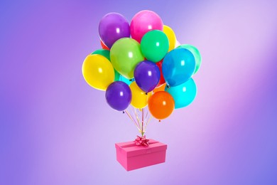 Many balloons tied to pink gift box on bright background