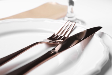Photo of Plates with golden cutlery on table, closeup