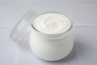 Delicious natural yogurt in glass jar on white table, closeup