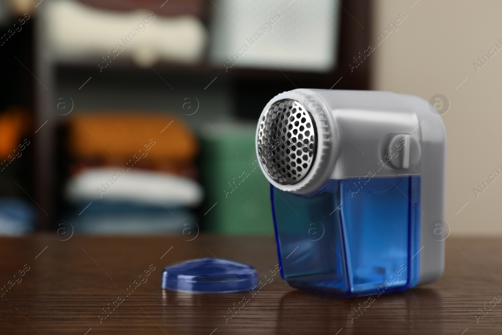 Photo of Modern fabric shaver on wooden table indoors, space for text