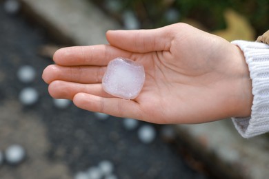 Woman holding hail grain after thunderstorm outdoors, closeup