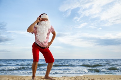 Photo of Santa Claus on beach, space for text. Christmas vacation