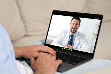 Online medical consultation. Man having video chat with doctor via laptop at home, closeup
