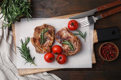 Photo of Delicious fried meat with rosemary, tomatoes and spices on wooden table, flat lay