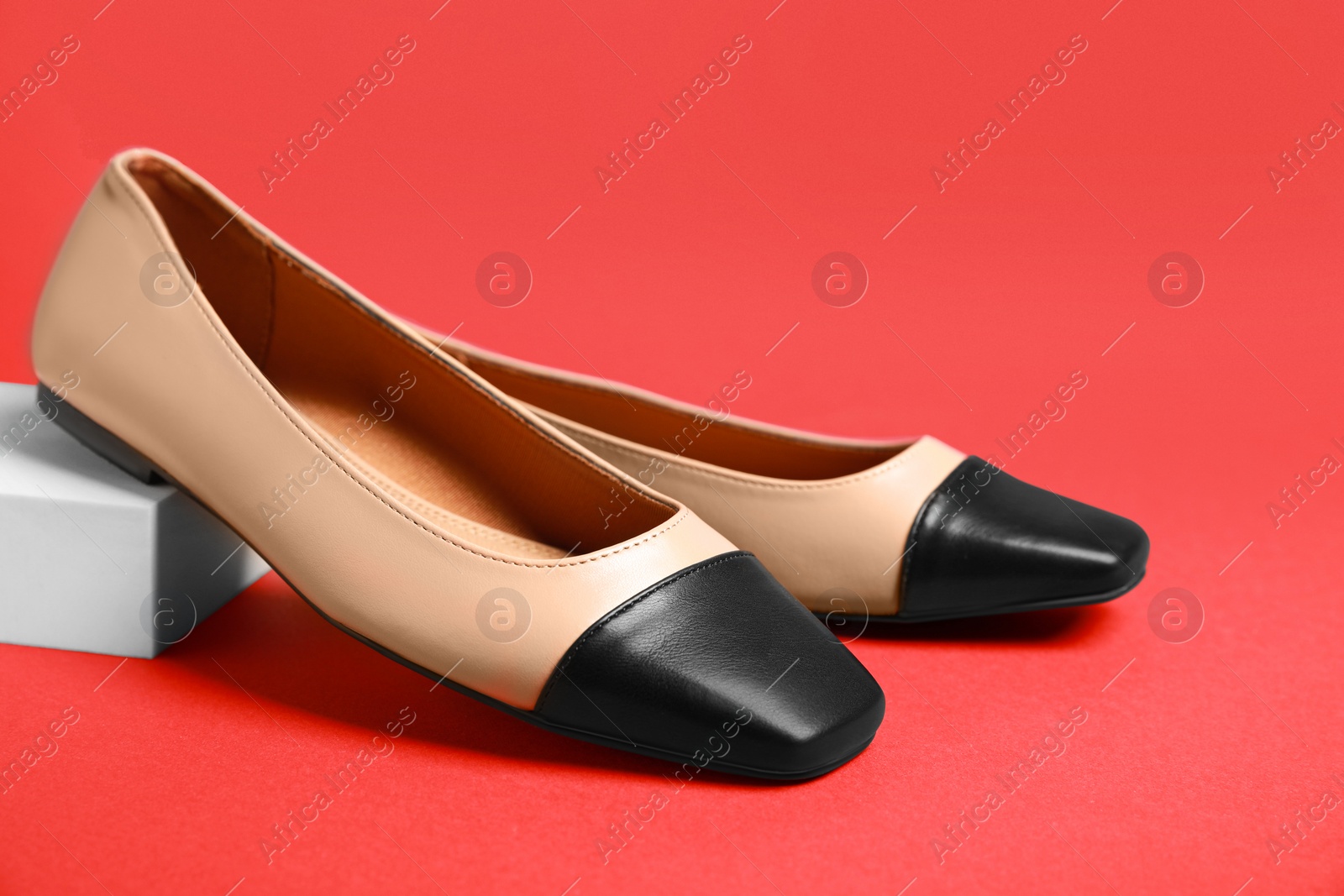 Photo of Pair of new stylish square toe ballet flats on red background