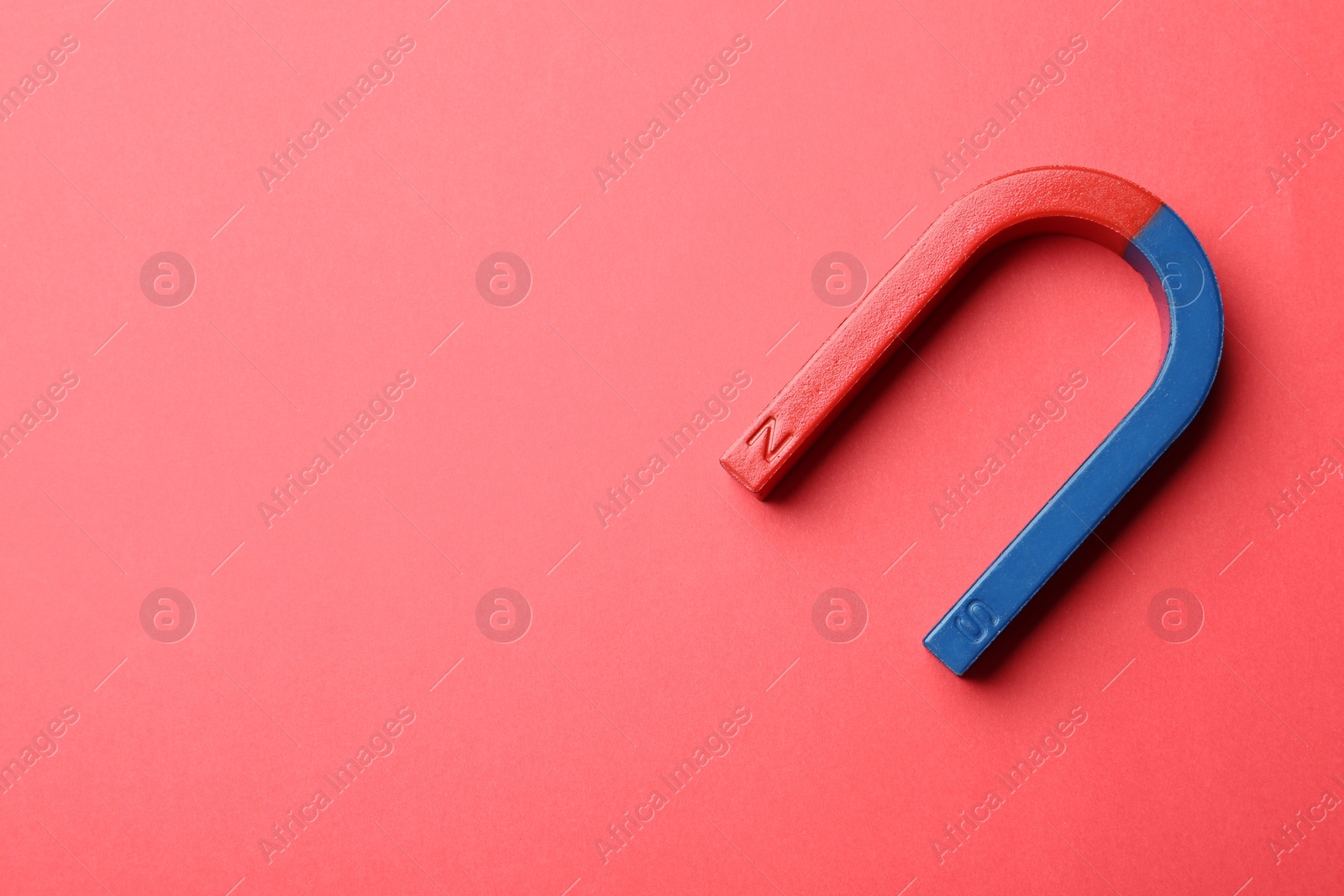 Photo of Red and blue horseshoe magnet on color background, top view with space for text