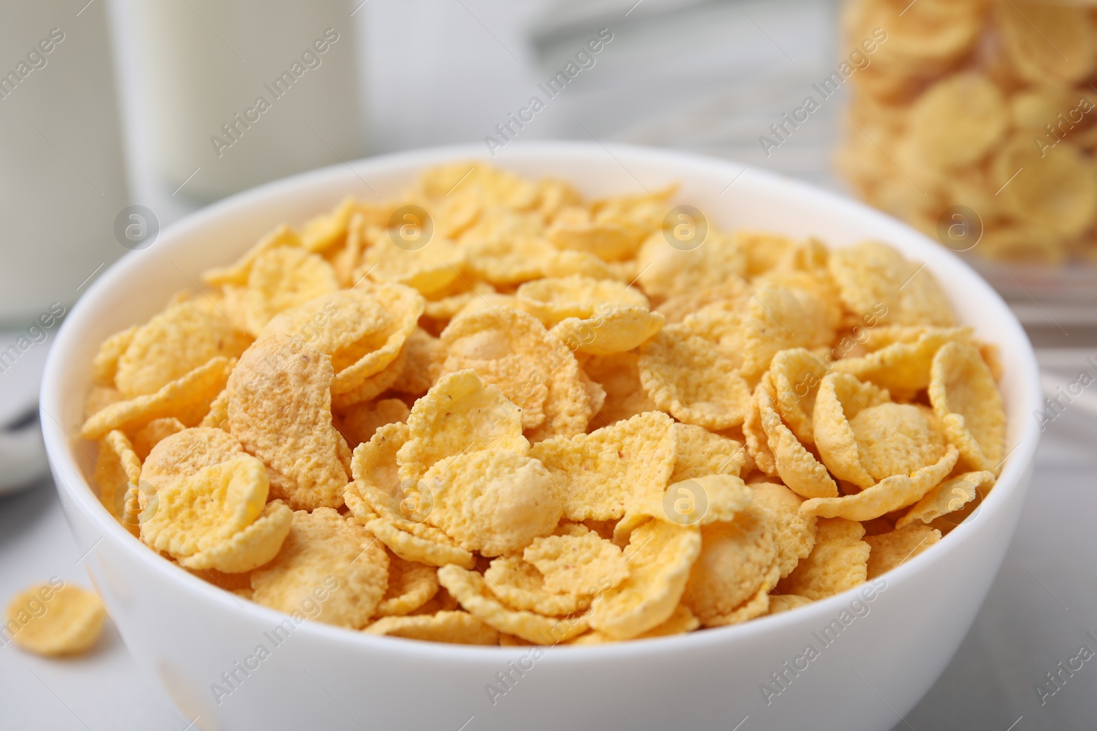 Photo of Tasty crispy corn flakes in bowl on table, closeup. Breakfast cereal