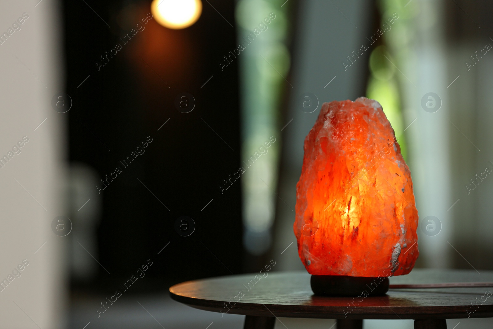 Photo of Himalayan salt lamp on table in room. Space for text