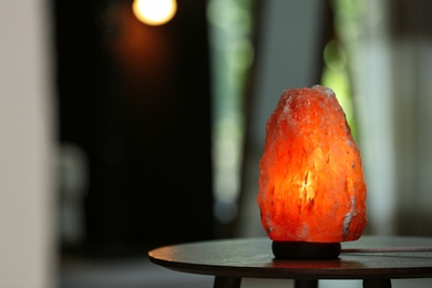 Himalayan salt lamp on table in room. Space for text