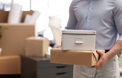 Man holding moving boxes in new office, closeup. Space for text