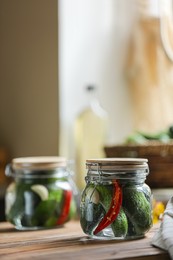 Photo of Jar of pickled cucumbers on wooden table. Space for text