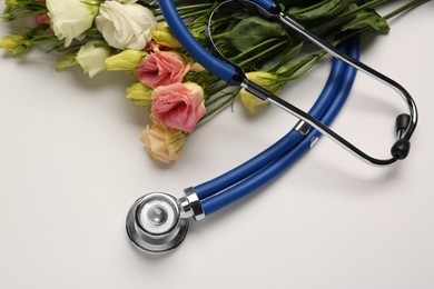 Photo of Stethoscope and flowers on white background. Happy Doctor's Day