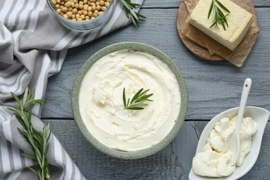 Photo of Delicious tofu cheese with rosemary and soy beans on grey wooden table, flat lay