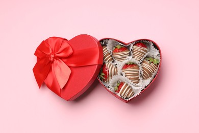 Photo of Heart shaped box with delicious chocolate covered strawberries on pink background, top view