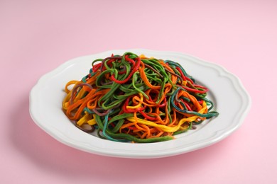 Photo of Plate of spaghetti painted with different food colorings on pink background