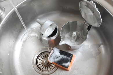 Photo of Moka pot (coffee maker) and sponge with foam in sink, above view