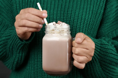 Woman holding mason jar of delicious cocoa drink with marshmallows, closeup