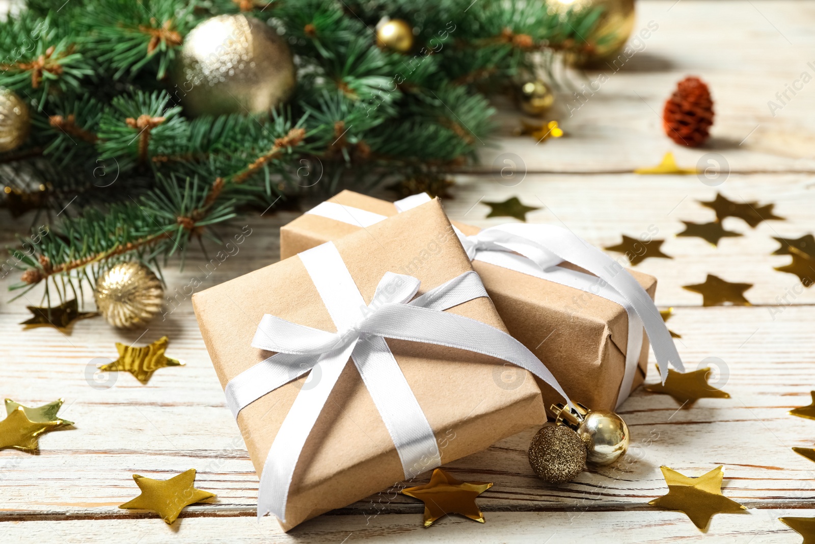 Photo of Gift boxes, fir branches, Christmas balls and shiny confetti on white wooden table