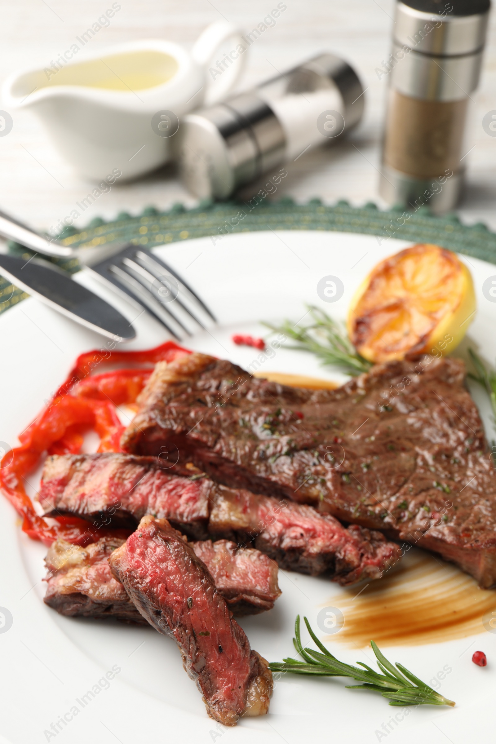 Photo of Delicious grilled beef steak with spices served on plate, closeup