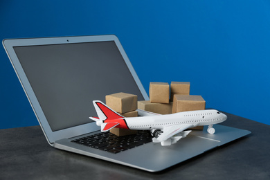 Laptop, airplane model and carton boxes on grey stone table. Courier service