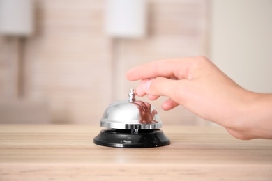 Photo of Woman ringing service bell on reception desk in hotel, closeup