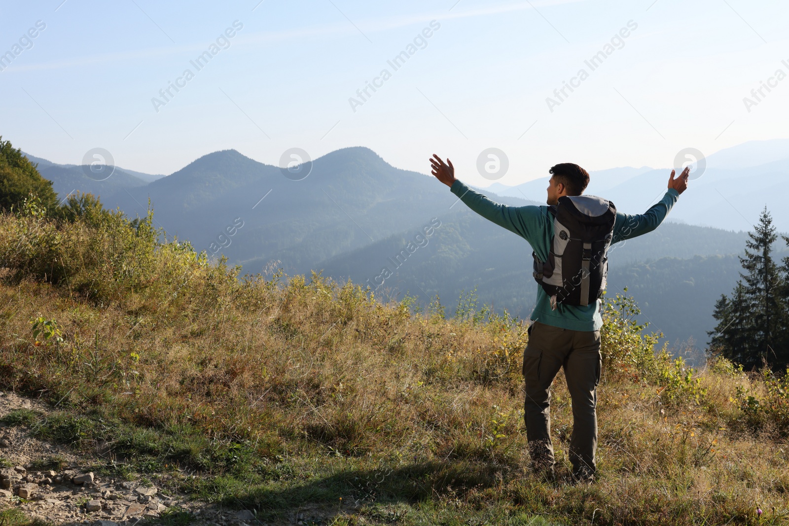 Photo of Tourist with backpack in mountains on sunny day, back view. Space for text