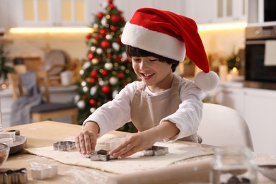 Photo of Cute little boy making Christmas cookies in kitchen