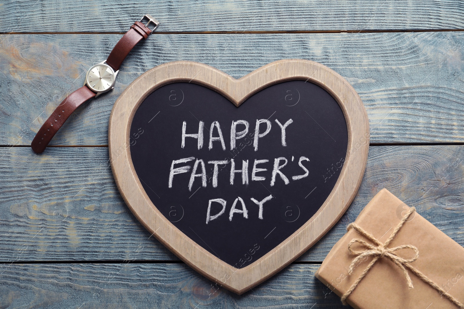 Photo of Gift box, watch and chalkboard with words HAPPY FATHER'S DAY on wooden background, top view