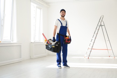 Full length portrait of professional construction worker with tools indoors