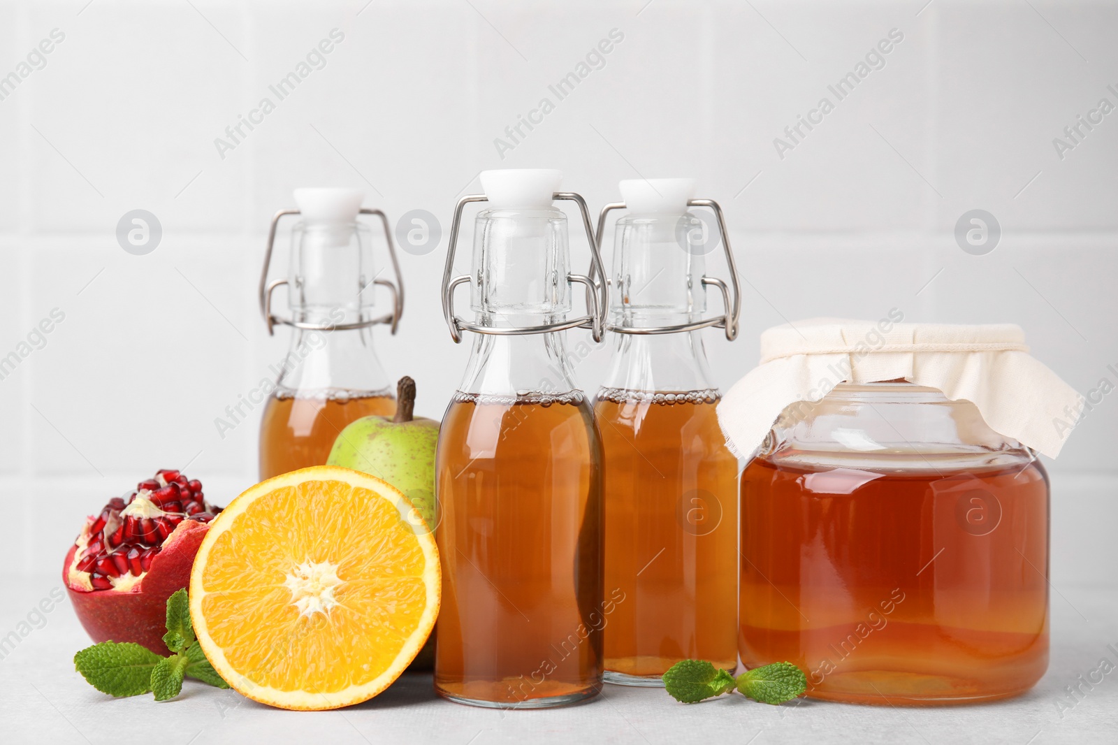 Photo of Tasty kombucha, fresh fruits and mint on white table