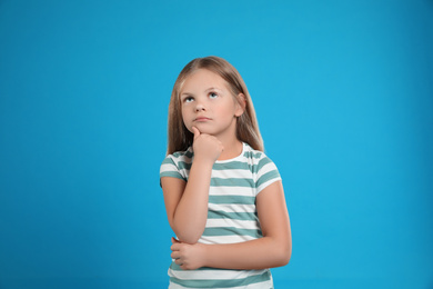 Portrait of emotional little girl on light blue background
