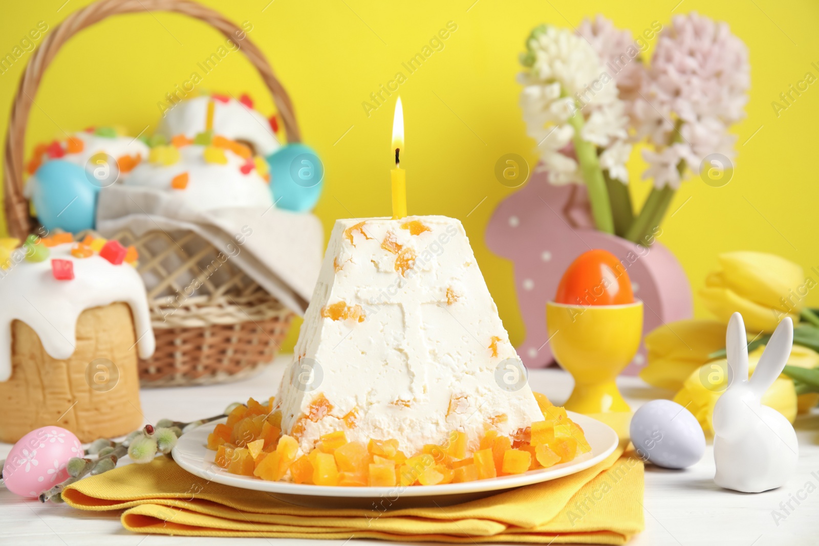 Photo of Traditional cottage cheese Easter paskha with dried apricot and burning candle on white wooden table