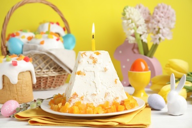 Traditional cottage cheese Easter paskha with dried apricot and burning candle on white wooden table