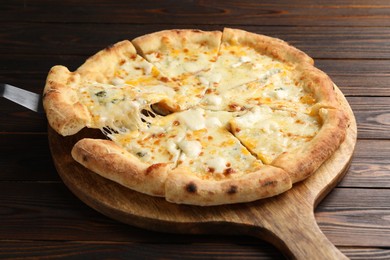 Photo of Taking piece of delicious cheese pizza at wooden table